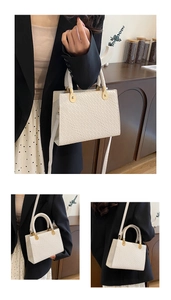Detail of cream woven pattern handbag with golden buckle and detachable shoulder strap