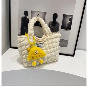 Close-up of cream puffer tote bag with bubble texture and yellow plush charm detail