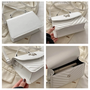 Detail of white quilted crossbody bag showing V-shaped stitching and butterfly hardware