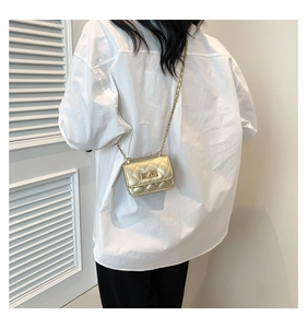 Detail einer mini goldfarbenen Stepptasche mit Metallic-Finish und Drehverschluss-Detail