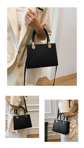 Detail of black woven texture leather bag with elegant gold metal hardware and top handle
