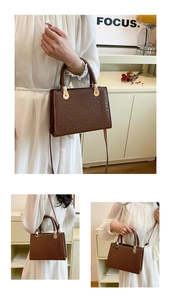 Detail of dark brown faux crocodile leather tote with sleek gold metal buckle hardware
