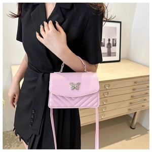 Détail d'un sac carré rose matelassé avec boucle papillon argentée et coutures en V