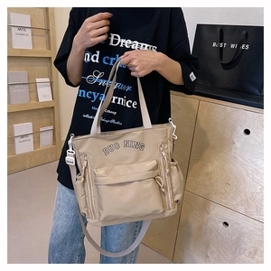 Detail of the multi-pocket structure and DUO NING logo on the beige crossbody bag