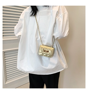 Detail of a mini gold quilted chain bag with a metallic finish and rectangular turn-lock