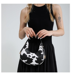 Detail of cow print crescent hobo bag with black leather strap and gold metal buckle