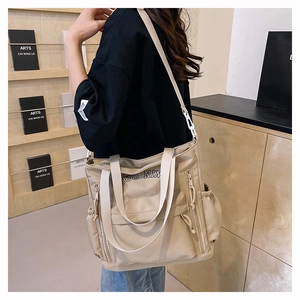 Macro detail of large beige crossbody tote bag with adjustable strap and side pockets