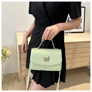 Détail du petit sac vert menthe avec fermoir papillon argenté et surpiqûres en V