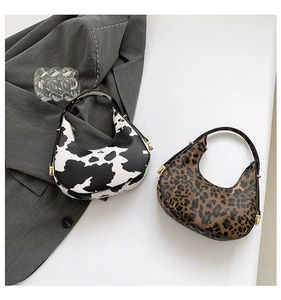 Close-up of hobo bags with cow and leopard prints featuring gold hardware detail