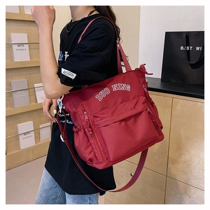 Detail of red nylon crossbody bag featuring white logo and multi-pocket functional design