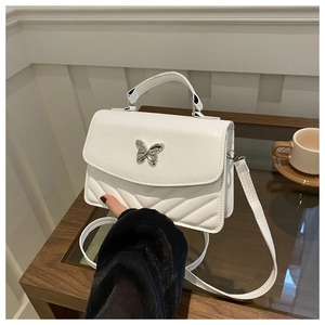 Gros plan d'un sac blanc en cuir avec boucle papillon argentée et motif matelassé en V