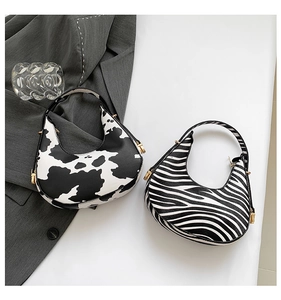 Detailed top view of half-moon underarm bags with cow and zebra print and gold zippers