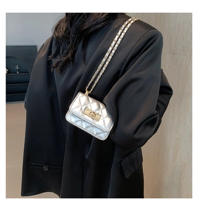 Dettaglio mini borsa trapuntata argento con catena oro indossata su un abito nero formale