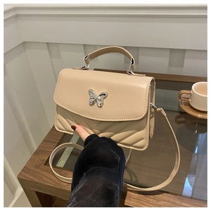 Détail du sac à bandoulière abricot avec fermoir papillon argenté et matelassage en V