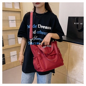 Detail of red nylon tote bag with dual zipper pockets and adjustable wide shoulder strap