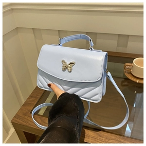 Détail du sac à bandoulière matelassé bleu clair avec fermoir papillon décoratif en argent