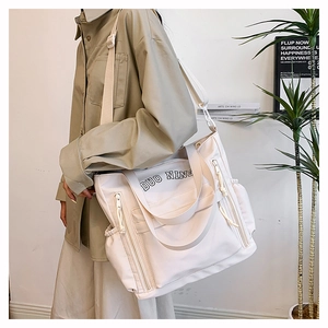Detail view of the large capacity beige canvas tote bag with side drawstring pockets