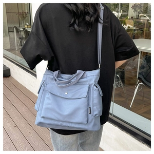 Détail du sac bandoulière en toile bleu clair avec multi-poches et cordon de serrage