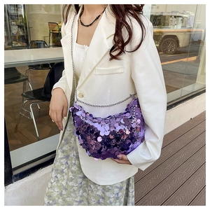 Dettaglio borsa a mezzaluna con paillettes viola e catena su blazer bianco