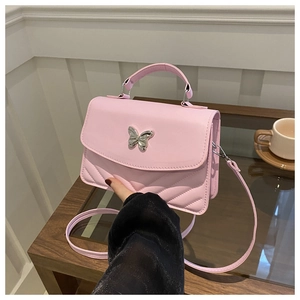 Vue détaillée d'un sac à main matelassé rose avec charm papillon argenté en gros plan