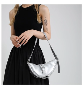 Close-up of metallic silver crescent bag with chain detail and buckle strap design