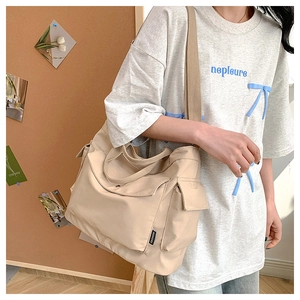 Detail of light beige large tote bag showing functional pockets and nylon fabric texture
