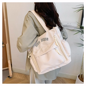 Detail of off-white nylon tote bag with multi-zipper pockets and black DUO NING print