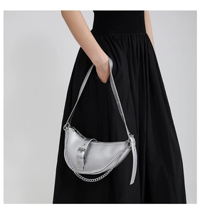 Silver crescent underarm bag with metal chain detail shown on a model in Y2K style