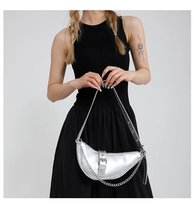 Detail of silver metallic half-moon bag with chain strap on a black dress