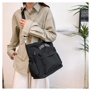 Detail shot of the large black nylon shoulder bag showing side pockets and wide straps