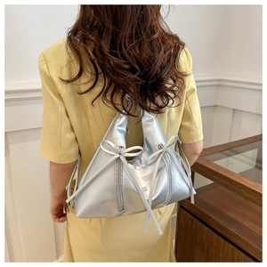 Detailed close-up of metallic silver tote bag with bow accents and triangular structure
