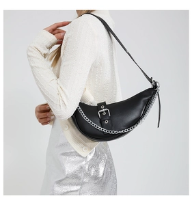 Close-up of black crescent shoulder bag with silver buckle and decorative metal chain