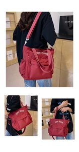 Detail view of red canvas crossbody bag with white DUO NING embroidery and wide strap