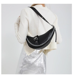 Detail of black leather crescent bag featuring silver chain and eyelet shoulder strap
