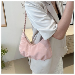 Detail of pink crescent bag showing ruched fabric texture and woven shoulder strap