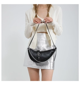 Detail of black crescent shoulder bag featuring a silver metal chain and belt buckle decor