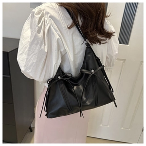 Detail of black tote bag with decorative bows and zipper accents on fashion model