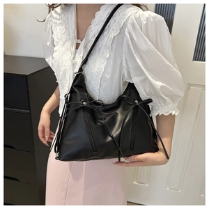 Dettaglio della borsa tote nera in morbida ecopelle con zip decorative e fiocchi trendy