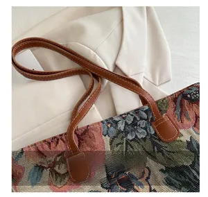 Dettaglio della borsa tote in jacquard floreale con manici in finta pelle marrone e cuciture