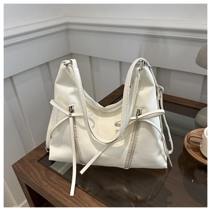 Close-up of cream PU leather tote bag featuring bow ribbons and vertical zipper details