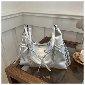 Close-up of a silver metallic bucket bag with bow ribbons on a stylish wooden table