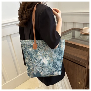 Detailed view of floral tapestry tote bag with brown leather straps worn on shoulder