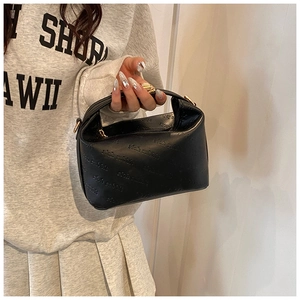 Detail of black leather handbag featuring embossed lettering and golden metal zipper