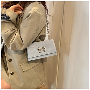 Détail du sac bandoulière bleu clair avec nœud argenté et bandoulière en chaîne