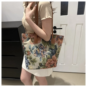 Detailed view of large embroidered floral tote bag worn on shoulder by a model