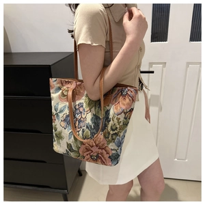 Detailed macro view of vintage floral tapestry tote bag with brown leather handles