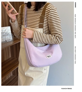 Lifestyle shot of light purple crescent nylon shoulder bag styled with striped outfit