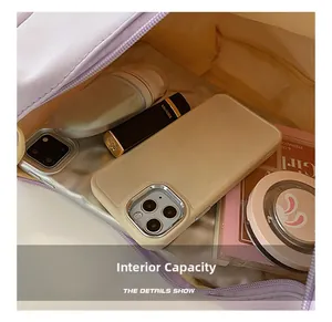 Detail view showing interior capacity of lilac saddle bag with phone and makeup