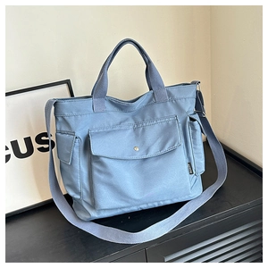 Light blue canvas travel bag with large front flap pocket and adjustable shoulder strap
