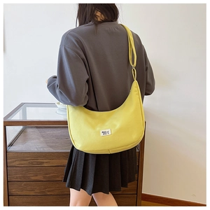 Side view of a bright yellow nylon crescent crossbody bag worn by a person